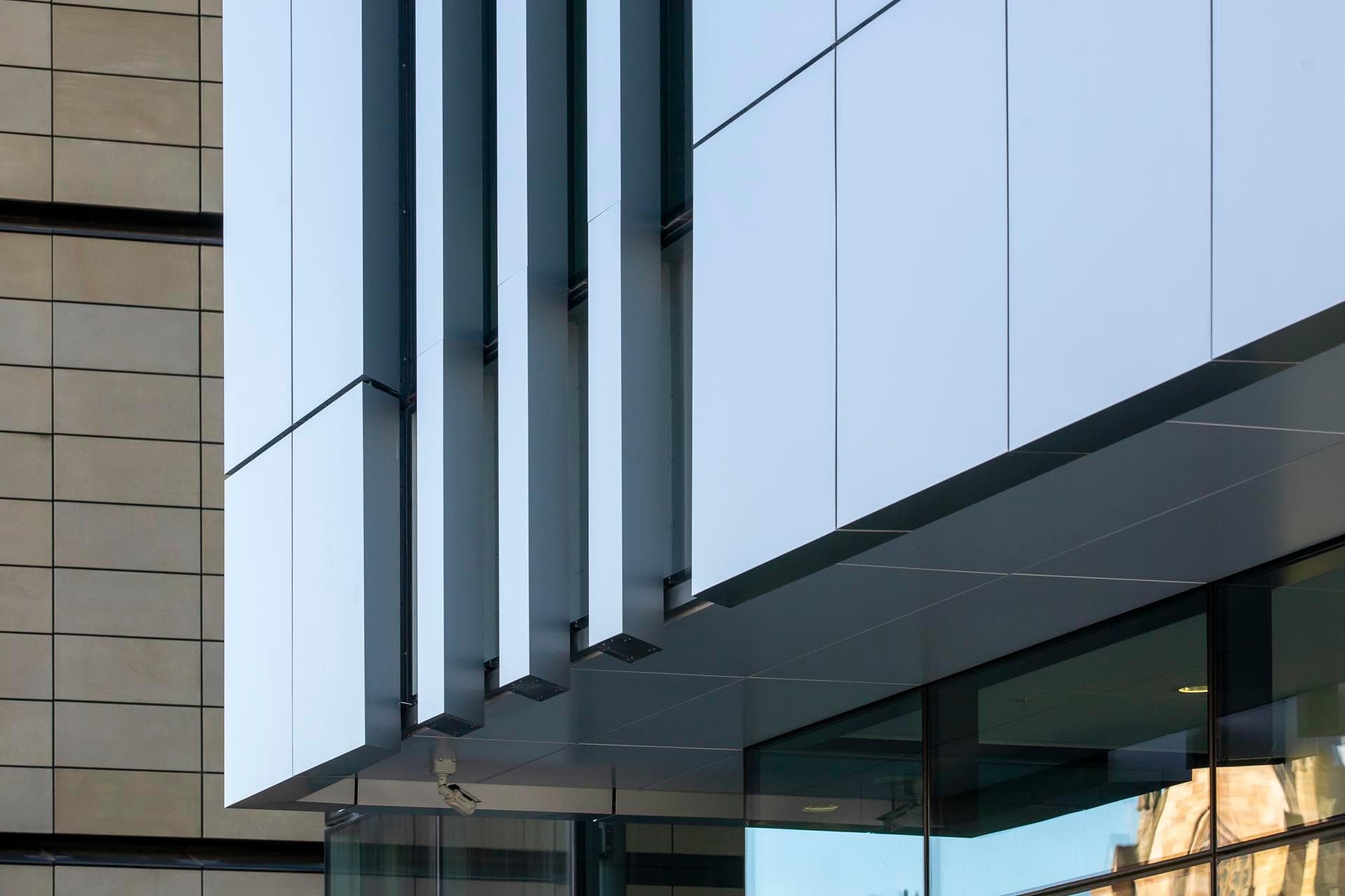 Close-up of Alpolic NC white façade panels with vertical fins on the Charles Perkins Centre, contrasted against beige cladding.