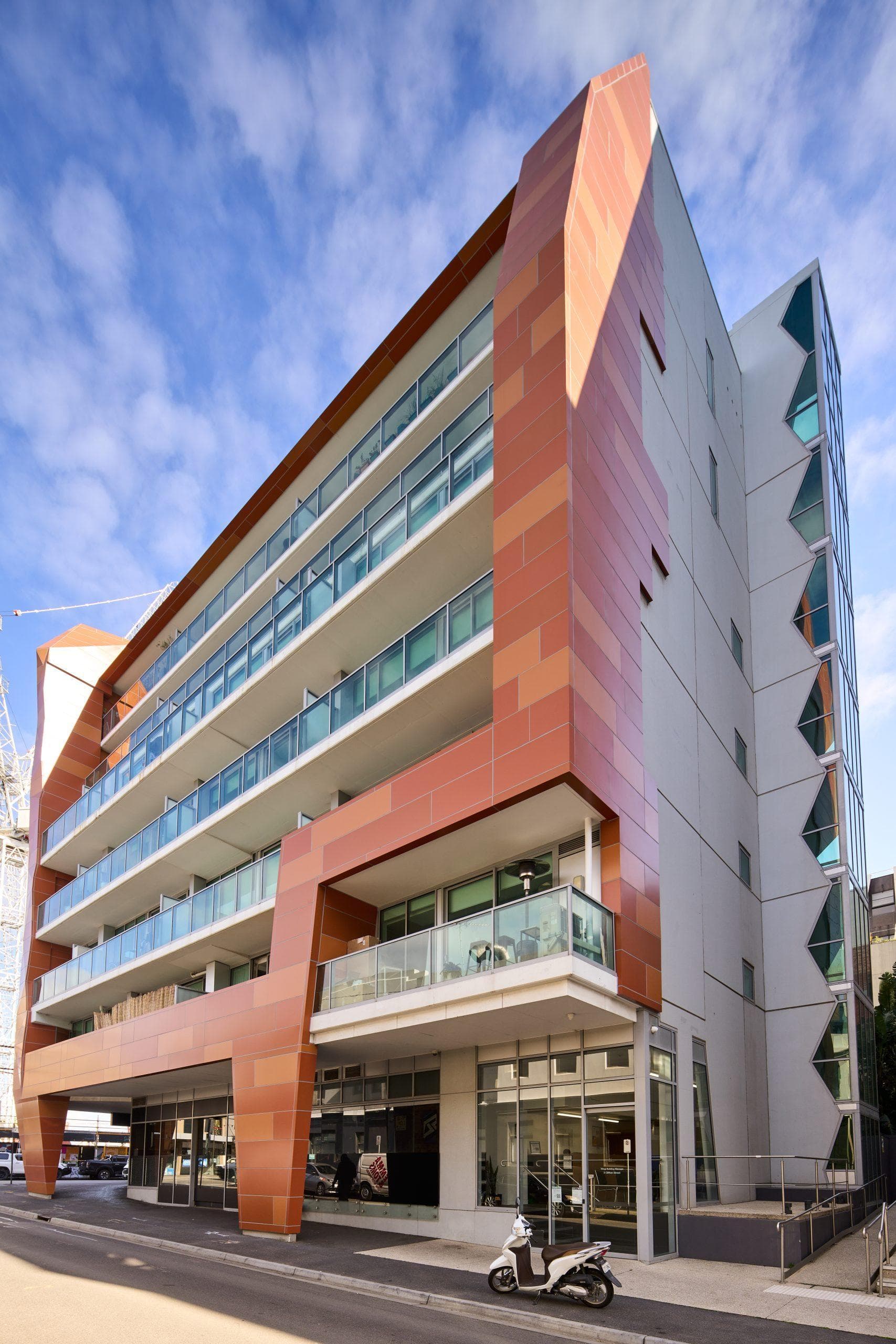 Angled view of Trilogi Apartments reclad with ALPOLIC™ NC/A1 aluminium panels in varied orange finishes